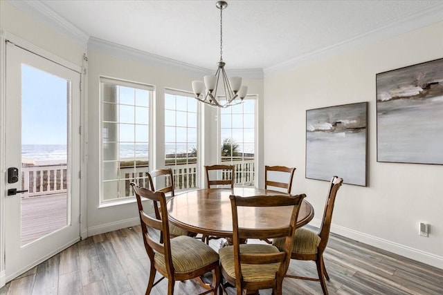 dining space with ornamental molding, dark wood-type flooring, a notable chandelier, and a water view