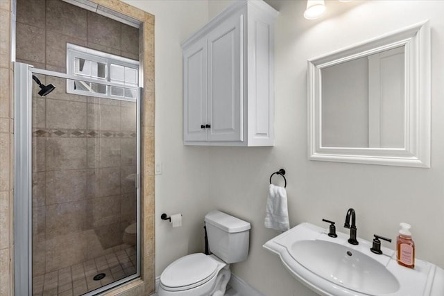 bathroom with toilet, a shower with shower door, and sink