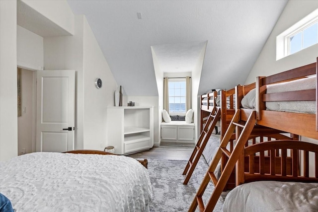 bedroom with hardwood / wood-style floors, vaulted ceiling, and multiple windows