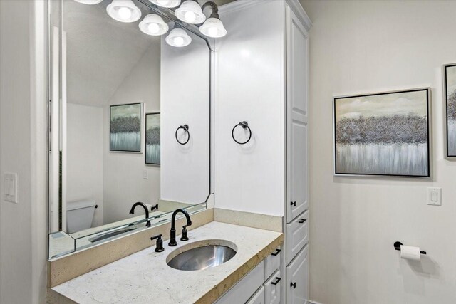 bathroom featuring vanity, vaulted ceiling, and toilet