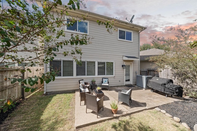 back house at dusk with an outdoor living space, a patio area, and central AC