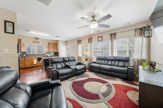 living room with hardwood / wood-style floors, ceiling fan, and sink