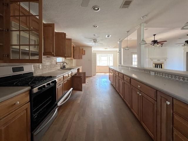 kitchen featuring gas range, sink, hanging light fixtures, hardwood / wood-style floors, and decorative backsplash