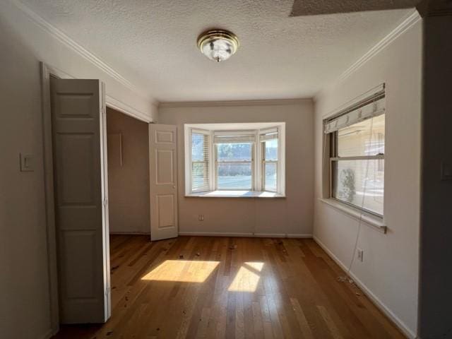 spare room featuring crown molding, hardwood / wood-style floors, and a textured ceiling