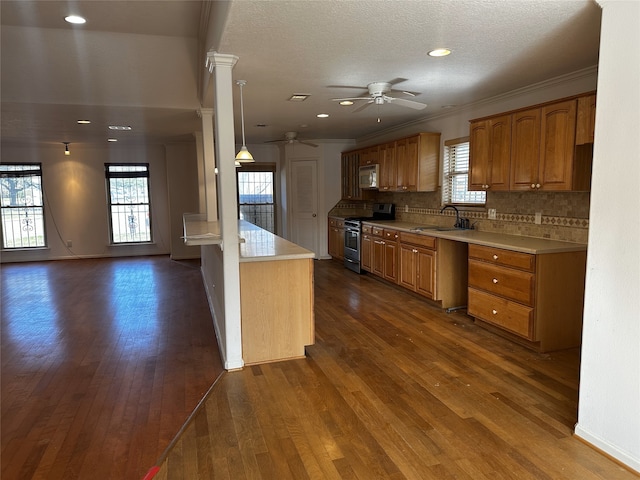 kitchen featuring ornate columns, appliances with stainless steel finishes, pendant lighting, tasteful backsplash, and sink