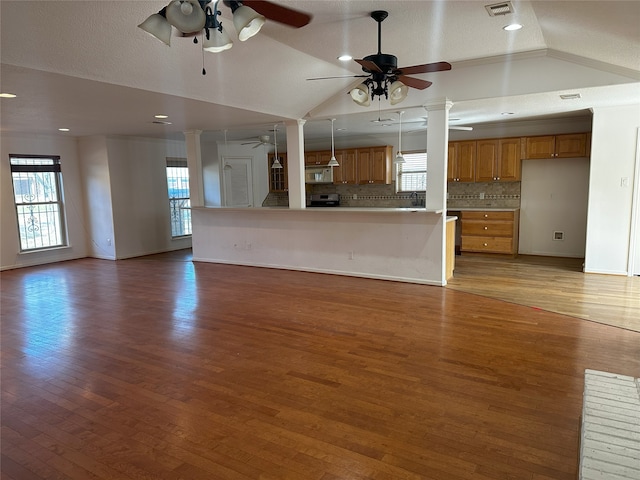 unfurnished living room featuring lofted ceiling, hardwood / wood-style flooring, and decorative columns