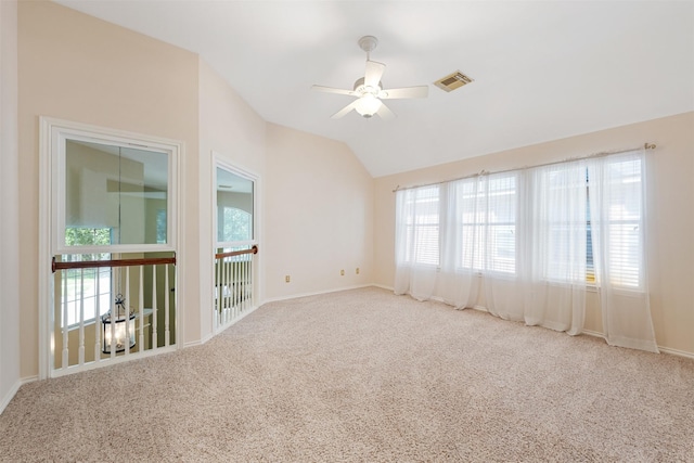 empty room featuring carpet flooring, ceiling fan, a healthy amount of sunlight, and lofted ceiling