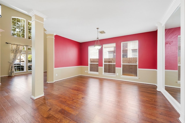 unfurnished room featuring ornate columns, dark wood-type flooring, and crown molding