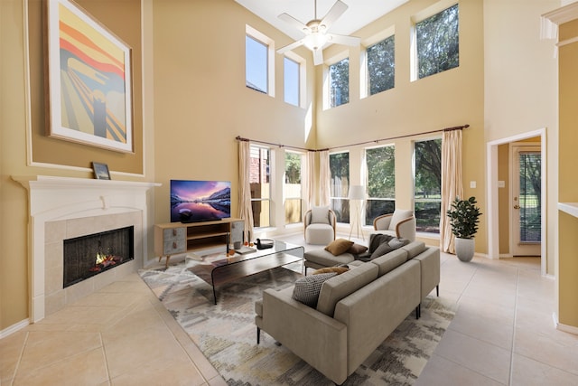 living room featuring a fireplace, light tile patterned floors, a towering ceiling, and ceiling fan