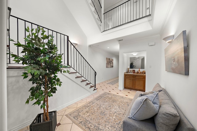 entrance foyer with a towering ceiling, crown molding, and light tile patterned flooring