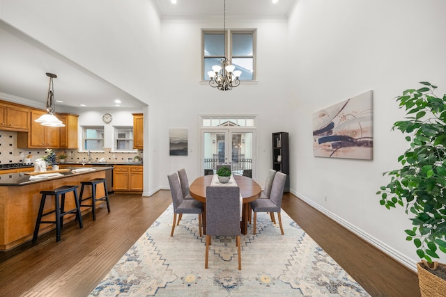 dining area featuring french doors, dark wood-type flooring, a high ceiling, and an inviting chandelier