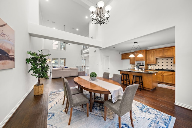 dining room featuring a towering ceiling, dark wood-type flooring, crown molding, and a notable chandelier