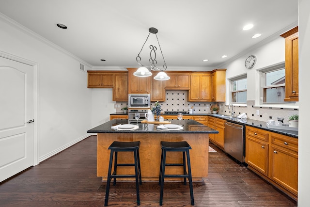 kitchen with dark hardwood / wood-style flooring, stainless steel appliances, crown molding, sink, and a kitchen island