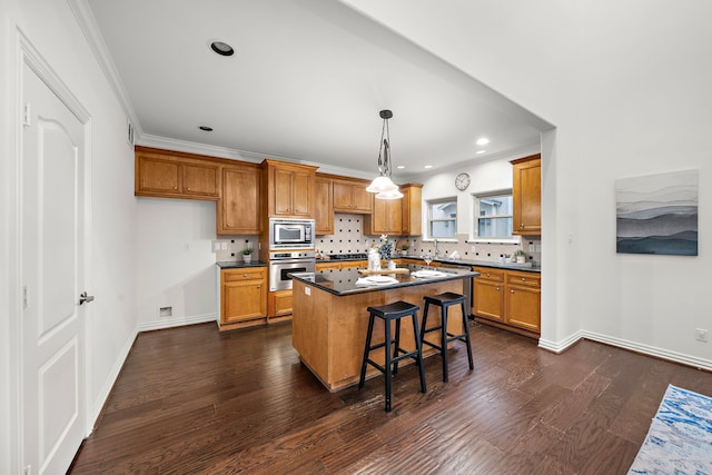 kitchen with a kitchen breakfast bar, dark hardwood / wood-style flooring, appliances with stainless steel finishes, a kitchen island, and ornamental molding