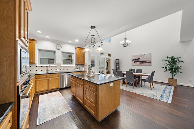 kitchen with sink, decorative backsplash, decorative light fixtures, a kitchen island, and stainless steel appliances