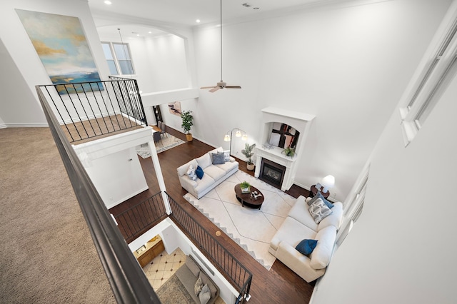 living room featuring ceiling fan, carpet floors, crown molding, and a towering ceiling