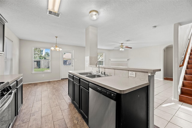 kitchen with sink, stainless steel appliances, pendant lighting, a center island with sink, and ceiling fan with notable chandelier