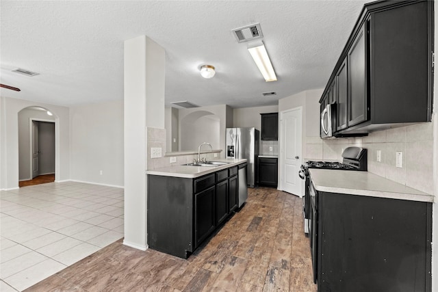 kitchen with decorative backsplash, light hardwood / wood-style floors, sink, and stainless steel appliances