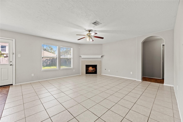 unfurnished living room with ceiling fan, light tile patterned floors, and a textured ceiling