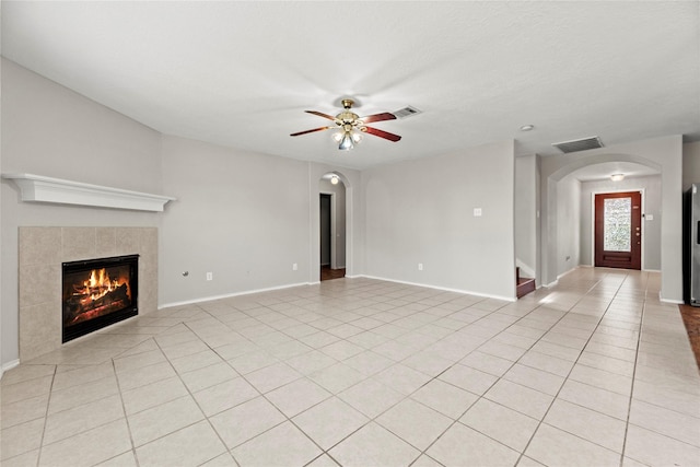 unfurnished living room with ceiling fan, light tile patterned floors, and a tiled fireplace