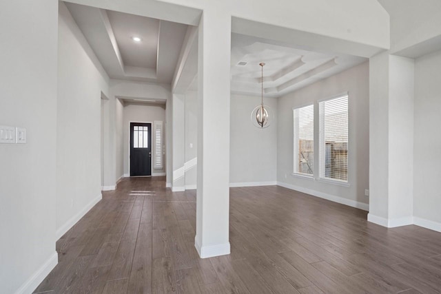 foyer featuring a raised ceiling, dark wood finished floors, baseboards, and an inviting chandelier