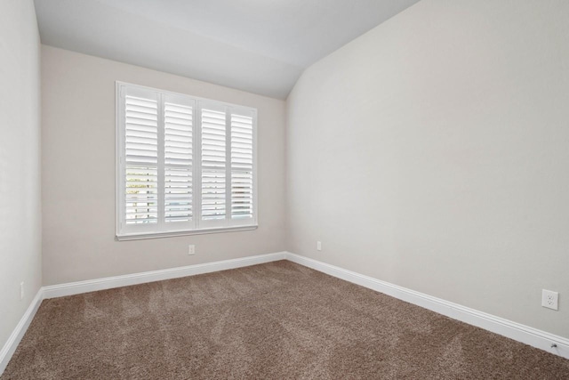 empty room featuring lofted ceiling, baseboards, and carpet