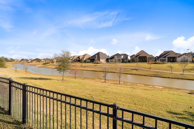 view of yard with a water view, fence, and a residential view