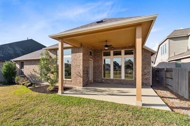 rear view of house featuring brick siding, fence, a ceiling fan, a yard, and a patio area