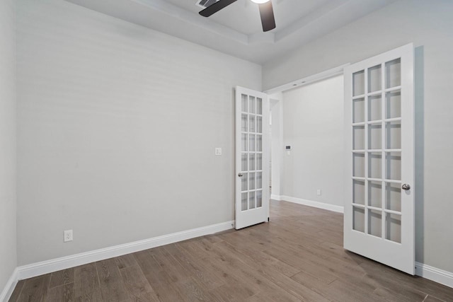 empty room with wood finished floors, visible vents, baseboards, french doors, and a raised ceiling