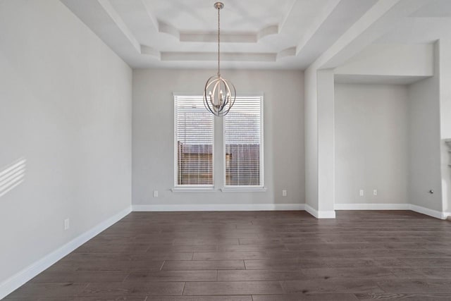 unfurnished dining area with a tray ceiling, dark wood finished floors, a notable chandelier, and baseboards