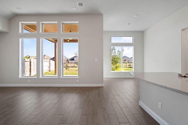 empty room featuring baseboards, visible vents, and dark wood finished floors