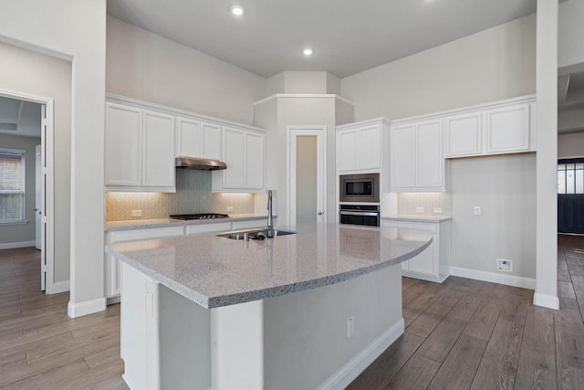 kitchen featuring a center island with sink, light wood-style flooring, appliances with stainless steel finishes, white cabinets, and a sink