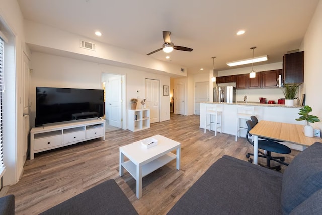 living room with light hardwood / wood-style flooring and ceiling fan