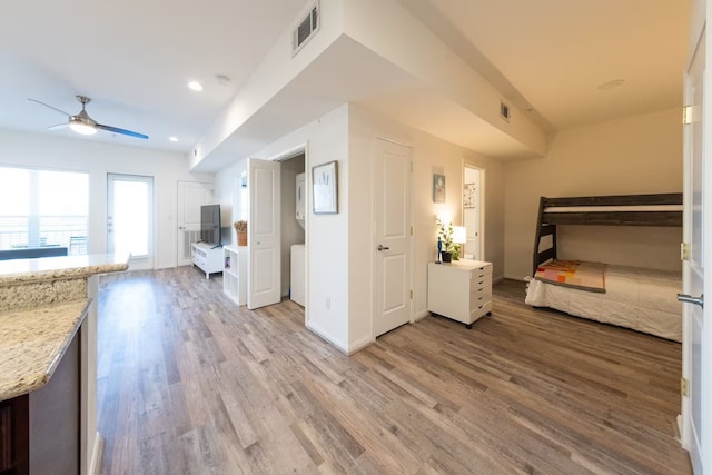 interior space with light stone countertops, light hardwood / wood-style floors, and ceiling fan