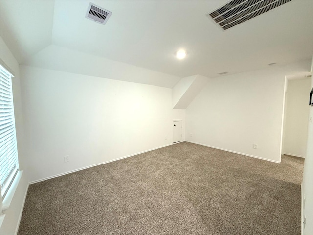 additional living space featuring dark colored carpet and lofted ceiling