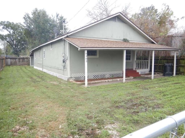 view of side of home featuring covered porch and a yard