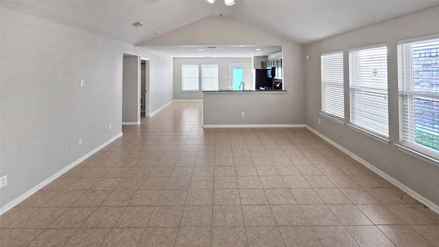 unfurnished living room featuring light tile patterned floors, vaulted ceiling, and sink