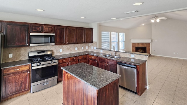 kitchen with a tile fireplace, sink, a center island, lofted ceiling, and appliances with stainless steel finishes