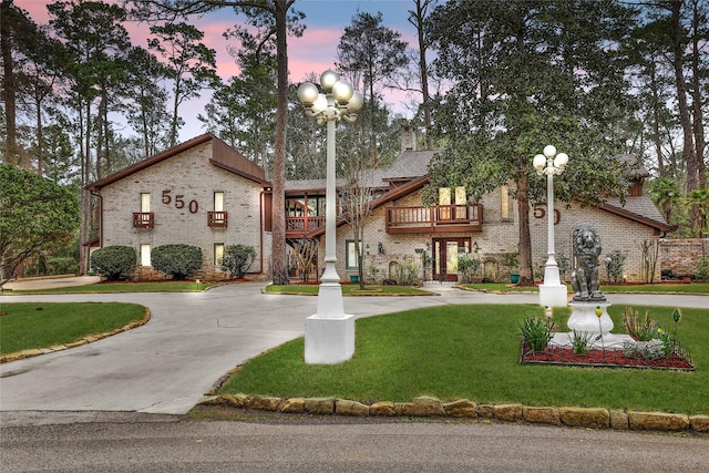 view of front of property with a balcony and a yard