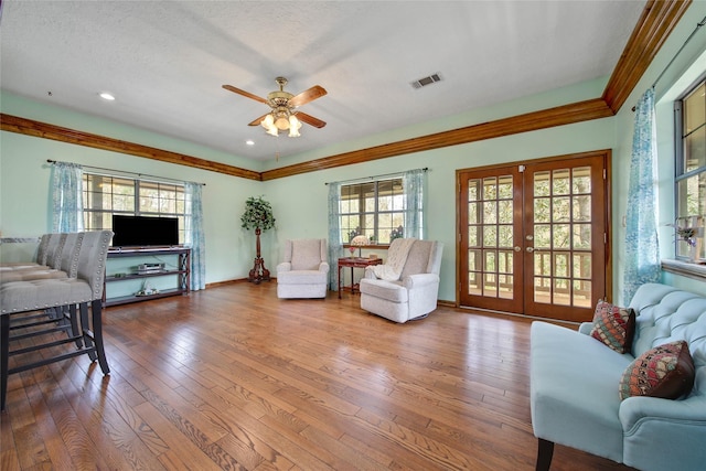 living room featuring a wealth of natural light, ceiling fan, french doors, and hardwood / wood-style floors