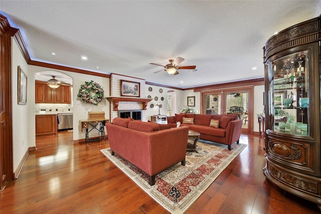 living room with ceiling fan, a fireplace, crown molding, and hardwood / wood-style flooring