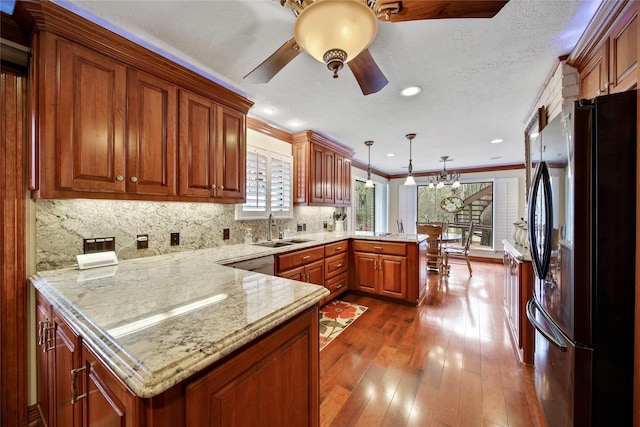 kitchen with sink, hanging light fixtures, kitchen peninsula, fridge, and ornamental molding