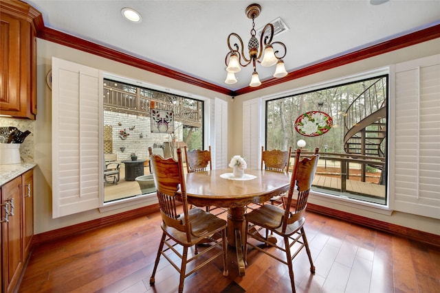 dining room featuring hardwood / wood-style flooring, crown molding, and a chandelier