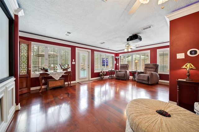 living room with a textured ceiling, ceiling fan, dark hardwood / wood-style flooring, and crown molding