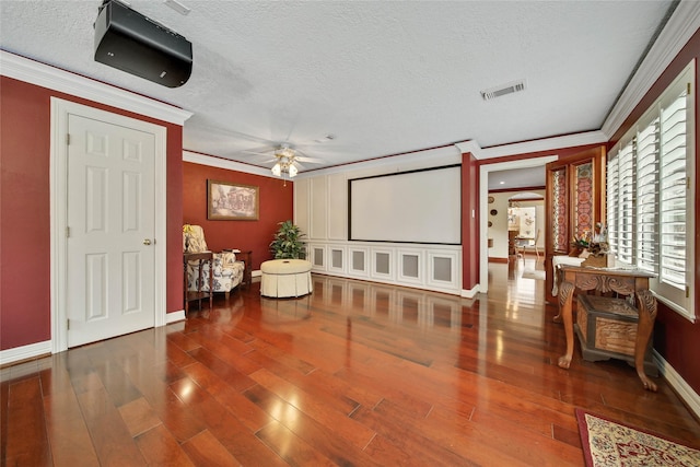 home theater with crown molding, ceiling fan, wood-type flooring, and a textured ceiling