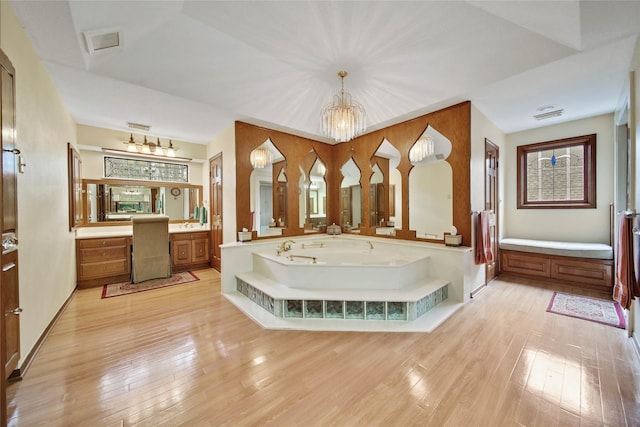 bathroom with a tub to relax in, vanity, wood-type flooring, and an inviting chandelier