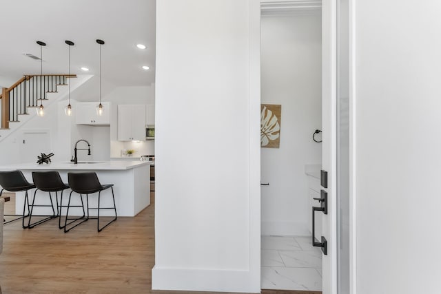 kitchen with appliances with stainless steel finishes, sink, white cabinets, hanging light fixtures, and a breakfast bar area