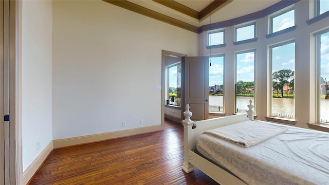 bedroom featuring dark hardwood / wood-style flooring, a water view, a high ceiling, and ornamental molding