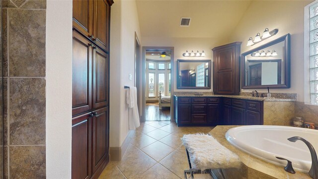 bathroom featuring tile patterned floors, vanity, and tiled bath