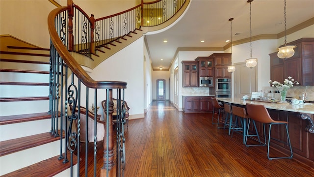 kitchen featuring decorative backsplash, appliances with stainless steel finishes, light stone countertops, crown molding, and pendant lighting